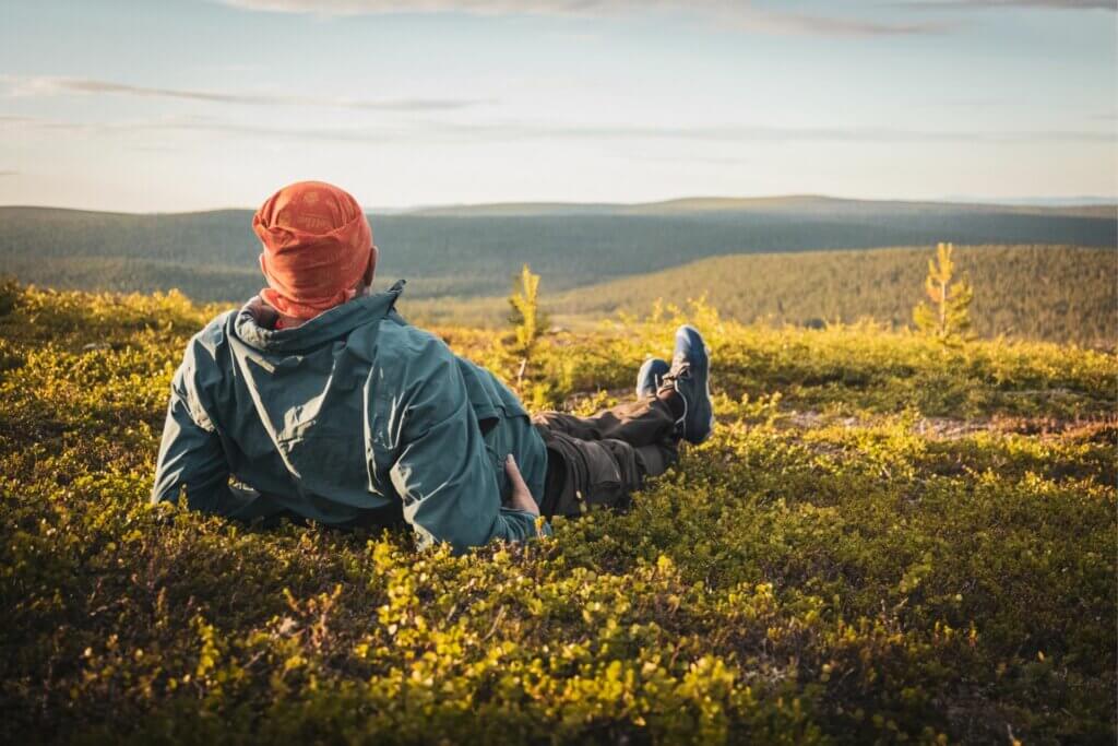 Retkeilijä rentoutuu ilta-auringossa tunturih laella.